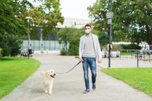 man in mask with labrador dog walking in city
