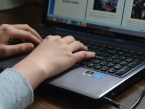 Hands typing on a laptop