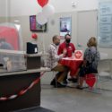 Three people sitting at a table wearing face masks talking in the adoption centre