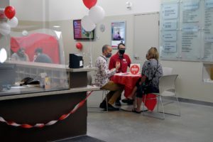 Three people sitting at a table wearing face masks talking in the adoption centre
